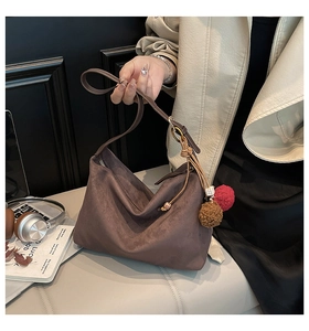 Detail of brown faux suede hobo bag with adjustable strap and plush pendant accessory