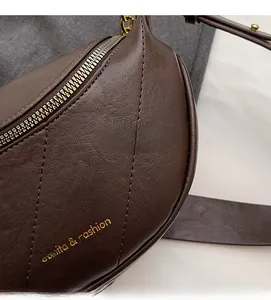 Dettaglio borsa a sella in pelle marrone scuro con trapuntatura a rombi e zip dorata