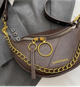 Dettaglio delle cerniere dorate e della catena su una borsa a sella marrone scuro