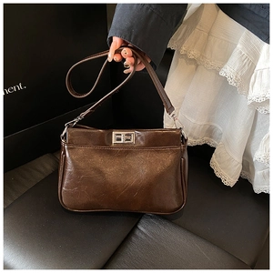 Dettaglio della borsa vintage marrone con chiusura girevole argento e trama raffinata