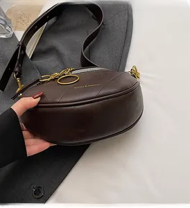 Dettaglio borsa a mezzaluna in pelle marrone scuro con trama litchi e metallo