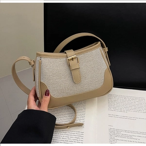 Close-up of canvas texture and khaki leather trim with adjustable metal buckle strap