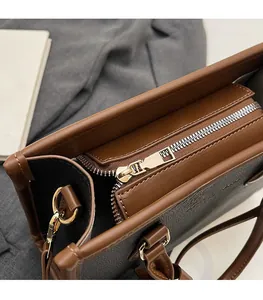 Detail of a two-tone leather tote with gold zipper and smooth stitching on black and brown