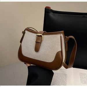 Detail of the vintage canvas and brown leather patchwork bag with a decorative metal buckle