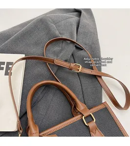 Detail of adjustable shoulder strap and leather texture on a contrast handbag