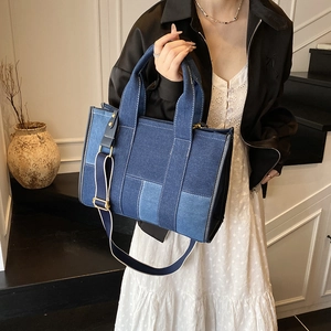 Detail of color-block patchwork denim tote bag showing stitching and woven strap