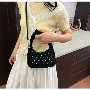 Close-up of black crescent bag with pearl heart patterns and ruched cloud handle