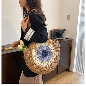 Detail of a round woven straw tote bag featuring a vibrant tricolor target pattern