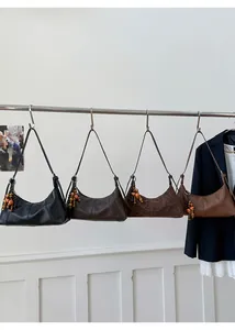 Détail de quatre sacs demi-lune minimalistes avec des breloques en perles de bois colorées