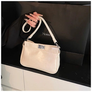 Dettaglio della borsa a spalla beige con chiusura a torsione in argento e trama liscia