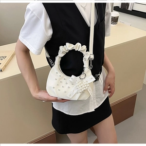 Detail of white cloud bag featuring ruffle handle and heart pearl bow accessory