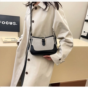 Detail of color-block canvas and black leather stitching on a retro baguette bag