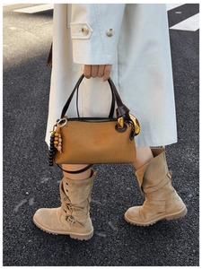 Close-up of brown matte Boston bag and beige buckle boots in a street style outfit