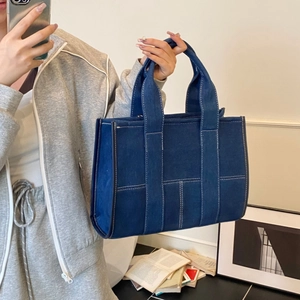 Detail of blue denim tote bag with white contrast stitching and sturdy top handles
