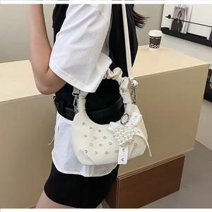 Detail of white ruched crescent bag with rhinestone dots and pearl bow charm