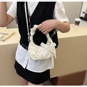 Detail of white pleated cloud bag featuring rhinestone accents and a pearl heart charm