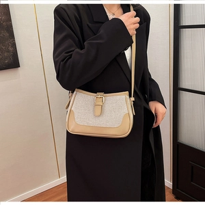 Detail of canvas crossbody bag with contrast leather trim on a model in a black suit