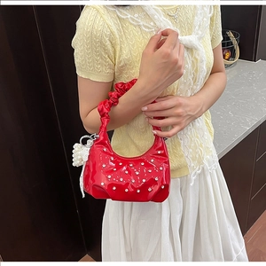 Detail of red patent leather cloud bag featuring pleated handle and silver rhinestone accents