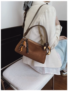 Detailed texture of brown suede Boston bag with wooden beads and golden hardware ring