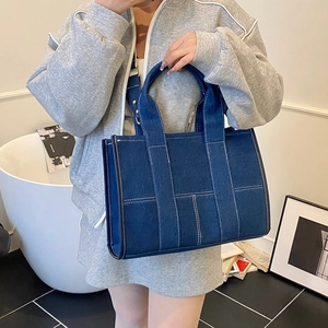 Detailed shot of dark blue denim tote bag with white stitching and adjustable strap