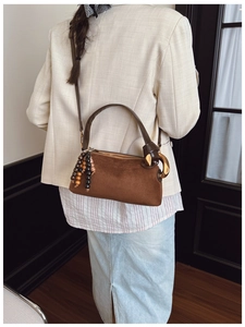 Detail of dark brown matte Boston bag featuring vintage wood bead tassels and golden buckle