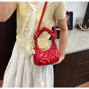 Macro detail of red heart handbag with cloud handle and sparkling pearl charm