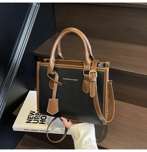 Detailed macro view of black lychee grain tote with brown leather trim and golden logo