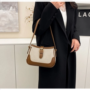 Detail of minimalist canvas shoulder bag with brown leather trim and golden metal buckle