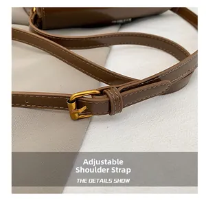Detail of a dark brown leather bag showing adjustable shoulder strap with gold metal buckle