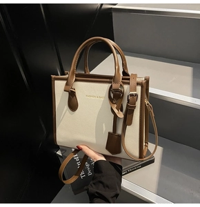 Detailed close-up of textured leather hand strap and gold lettering on contrast handbag