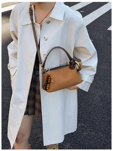 Close-up of retro brown frosted suede shoulder bag with wooden bead tassel details