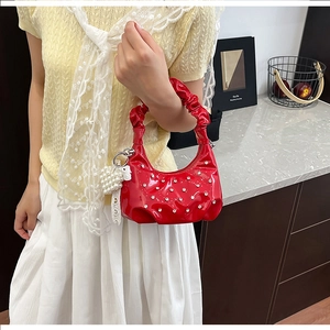 Detail of red patent leather cloud bag with rhinestones and heart pearl charm