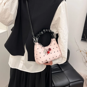 Pink satin dumpling bag with black ruffle handle and cherry pendant crossbody style