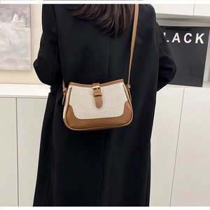 Detail of color-block canvas and leather shoulder bag shown on a black blazer
