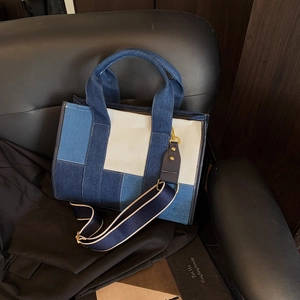 Detail of multi-color denim patchwork tote bag with gold hardware on a seat