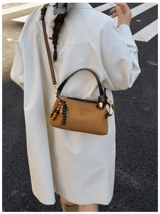 Brown matte Boston bag detail featuring golden metal ring and wooden bead pendant
