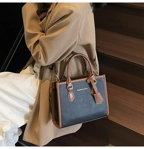 Brown and black tote bag with gold lettering shown on a model wearing a beige trench coat
