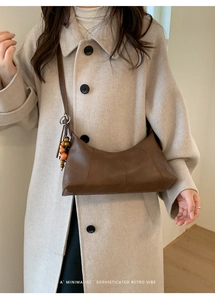 Détail du sac hobo en cuir marron avec surpiqûres verticales et accessoire porte-clés perlé