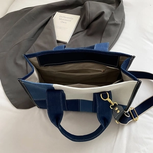 Detail view of large denim tote bag with internal zip pocket and adjustable strap