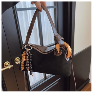Detail of suede Boston bag featuring chunky gold chain link and wooden bead charms
