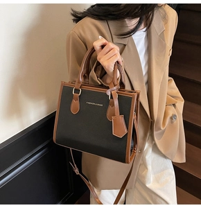 Close-up of contrast leather handbag with gold buckle and adjustable shoulder strap