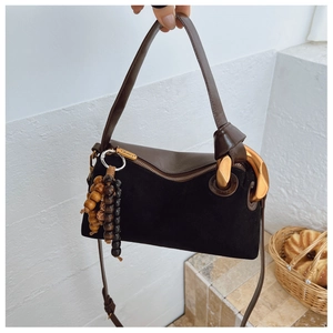 Detail of matte black suede and brown leather Boston bag with decorative wood beads