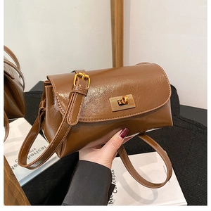 Detail of a brown vintage wax-texture leather bag featuring a gold rectangular twist lock
