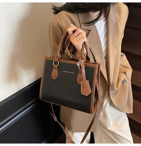 Detail shot of the two-tone leather handbag featuring gold hardware and logo printing