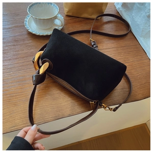 Macro view of matte black Boston bag with decorative gold metal ring and brown leather strap