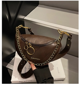 Dettaglio di una borsa a sella in pelle marrone con catena dorata e doppia zip ad anello