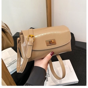 Close-up of khaki shoulder bag with gold rotating clasp and adjustable strap detail