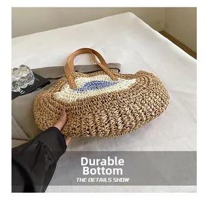 Detail showing durable woven bottom and leather handles of the round straw beach shoulder bag