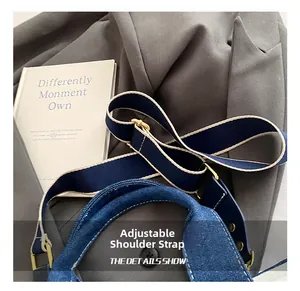 Detail of adjustable woven shoulder strap with gold buckle on denim handbag