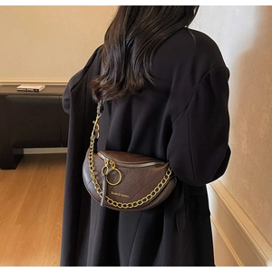 Vista dettagliata di una borsa a tracolla in pelle marrone scuro indossata da modella